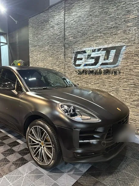 سيارة بورشه سوداء مطفية أمام شعار ESD على الجدار الحجري